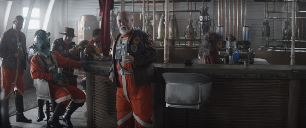 New Republic pilots including Trapper Wolf (Dave Filoni, wearing hat), Captain Carson Teva (Paul Sun-Hyung Lee, in center) with Bartender (Misty Rojas) in a scene from The Mandalorian