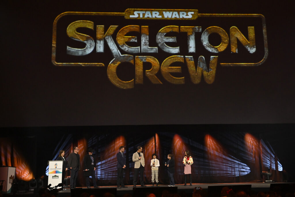 Kathleen Kennedy, John Favreau, Dave Filoni, Presenter Ali Plumb, Jude Law, Ravi Cabot Conyers, Robert Timothy Smith and Kyrianna Kratter onstage during the studio panel for Skeleton Crew at the Star Wars Celebration 2023 in London