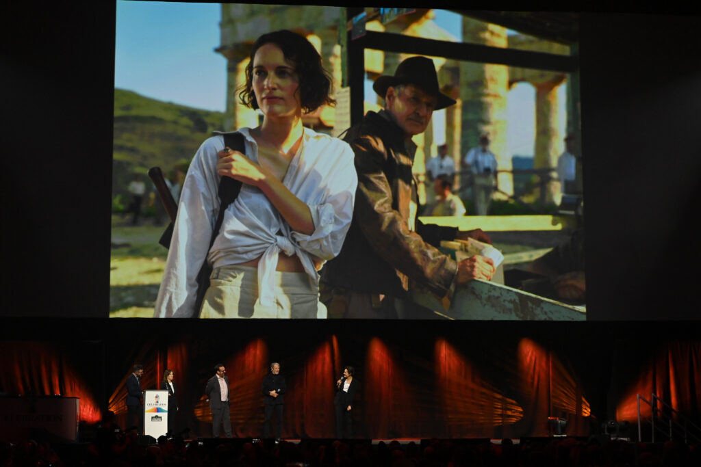 Ali Plumb, Kathleen Kennedy, Director James Mangold, Mads Mikkelsen and Phoebe Waller-Bridge onstage during the Indiana Jones and the Dial of Destiny presentation during the studio panel at Star Wars Celebration 2023 in London at ExCel on April 07, 2023 in London, England. On screen: Phoebe Waller-Bridge and Harrison Ford.