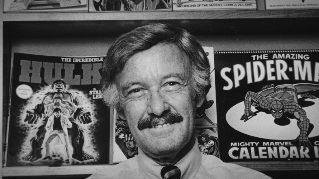 Stan Lee smiles in front of his prized comic books in this archival photo.