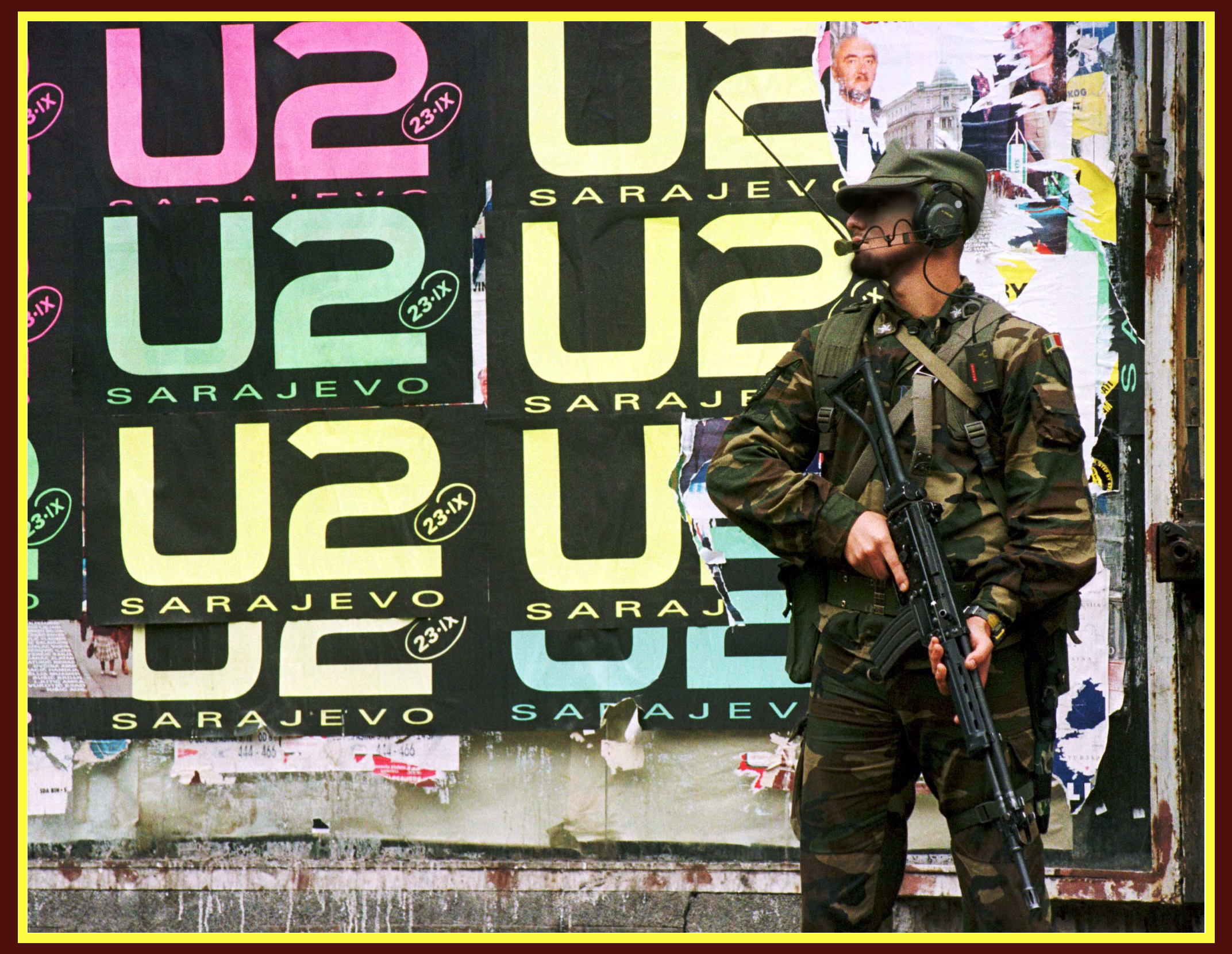 An Italian peacekeeper holds his rifle as he stands in front of wall covered with U2 posters in center Sarajevo September 21. The Irish band U2 will play at the Kosevo stadium on September 23 in Sarajevo's first major post-war rock concert in Kiss the Future.