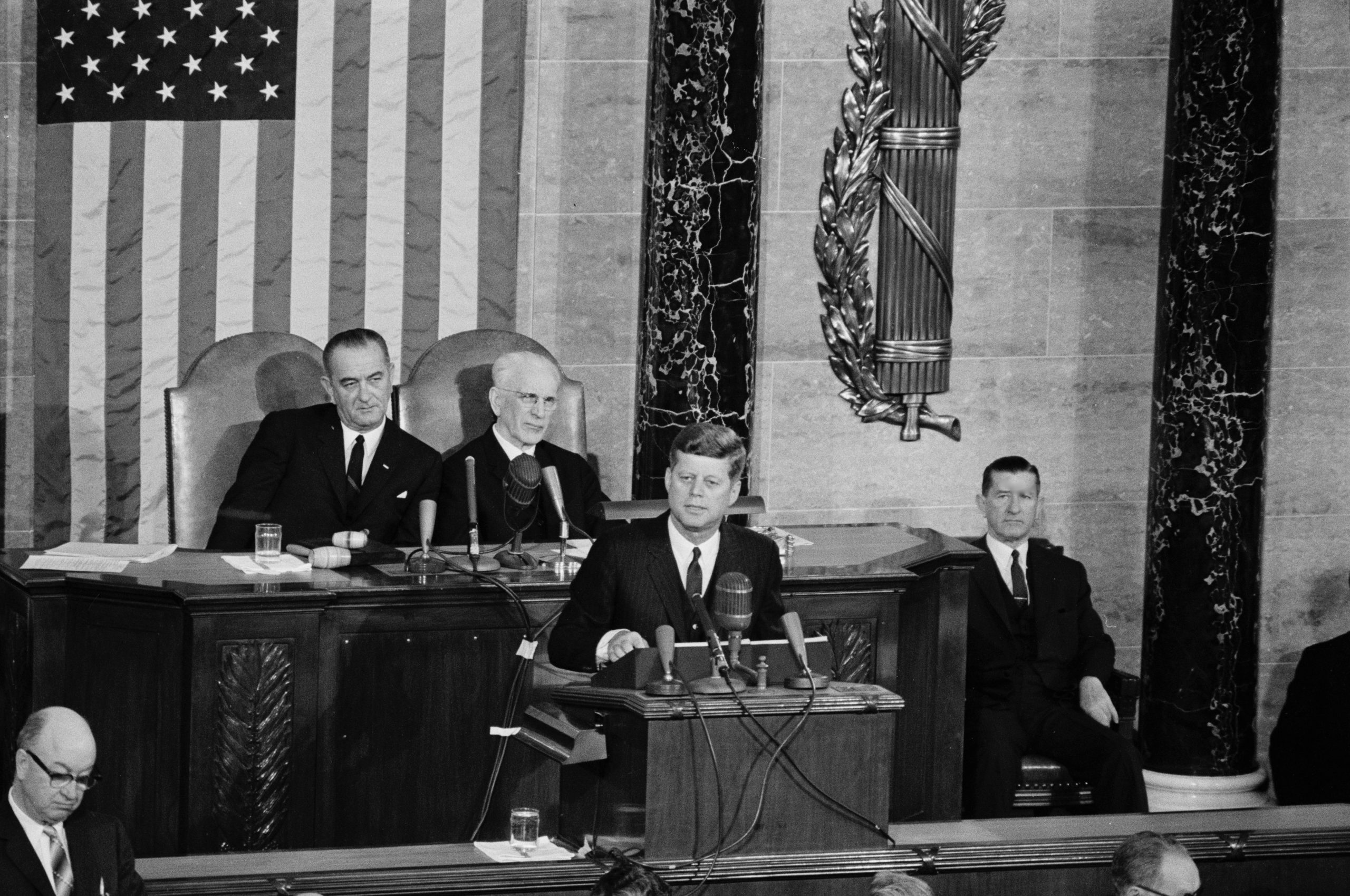 A photo still in An American Vice President: President John F. Kennedy delivering his annual address to Congress on the State of the Union in 1963. Vice President Lyndon B. Johnson (left) and Speaker of the House John W. McCormack sit behind him.